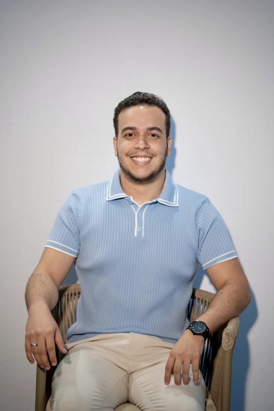 Tarcio sentado, de polo azul, sorrindo